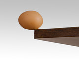 an egg teetering on the brink of a counter