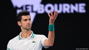 novak djokovic holding a hand in the air looks like he is questioning a call by the judge vocabulariio en inglés