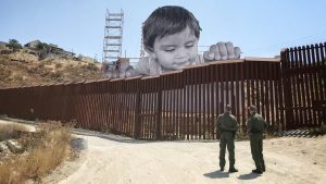 kid looking over the mexico-u.s. border wall